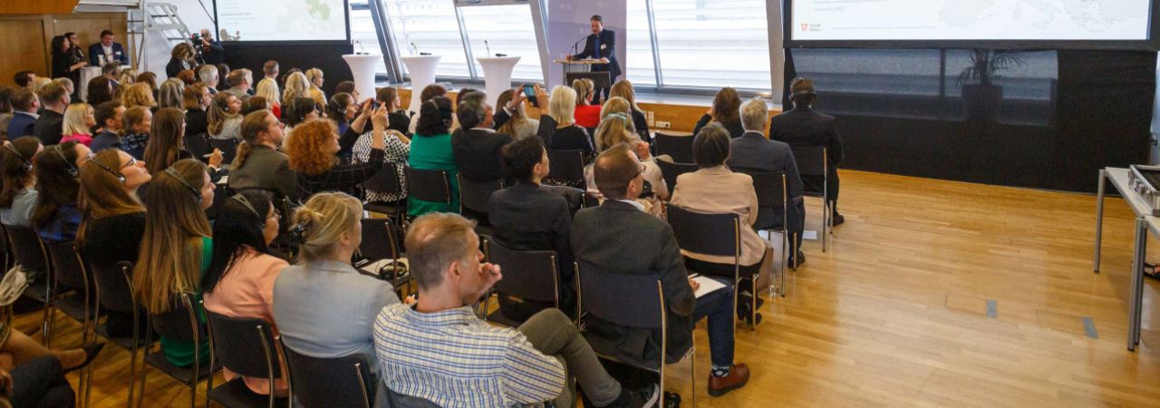 Konferenz-Publikum hört einem Vortragenden zu.