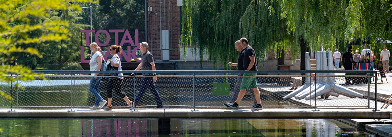 Menschen spazieren über eine Brücke über einem Teich