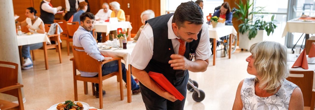 Келнер обслужва посетителка в ресторанта за хора с деменция